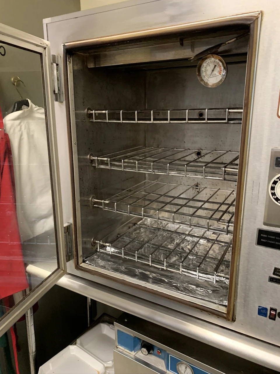 Second oven-interior view, with lighter metal surfaces, remaining spots and foil over the base